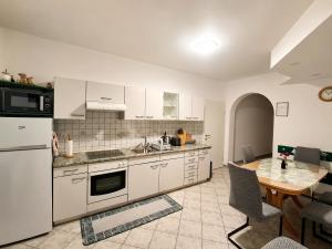 a kitchen with white cabinets and a table and a dining room at Apartment CDR in Zreče