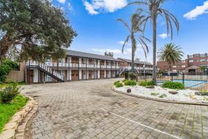 a building with palm trees and a courtyard at Frankston Bay Motel in Frankston