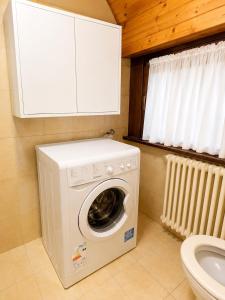 a washing machine in a bathroom next to a toilet at Dolomiti House in Pinzolo
