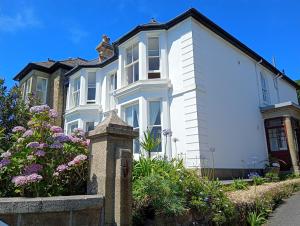 a white house with flowers in front of it at Mount Royal - Penzance in Penzance