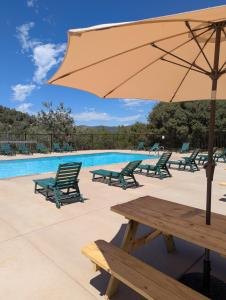 a picnic table with an umbrella next to a pool at Wildhaven Yosemite Glamping in Mariposa