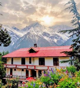 a house with a red roof with mountains in the background at The Kailash Glint in Kalpa