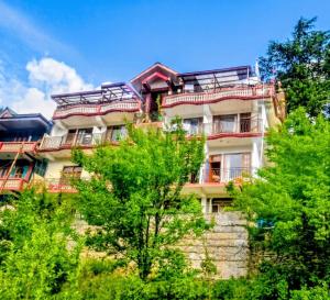 a tall building with trees in front of it at The Kailash Glint in Kalpa