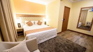 Un dormitorio con una cama, una silla y un espejo. en Hotel Alles Blau, en Pelotas