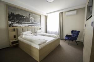 a bedroom with a large bed and a blue chair at Hotel Slezská in Muglinov