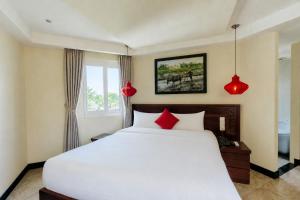 a bedroom with a large white bed with red pillows at River Suites Hoi An in Hoi An