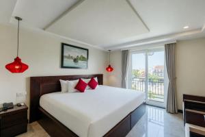 a bedroom with a large bed and a window at River Suites Hoi An in Hoi An