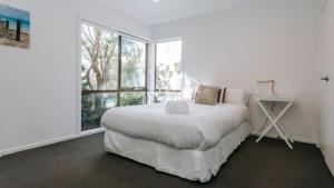 a white bedroom with a bed and a window at Blissful Escape in Portsea +26 photos