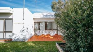 two white chairs sitting on a patio in front of a house at Blissful Escape in Portsea