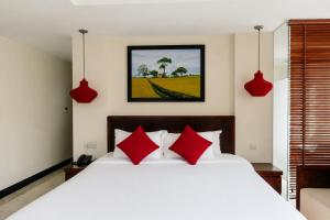 a bedroom with a white bed with red pillows at River Suites Hoi An in Hoi An
