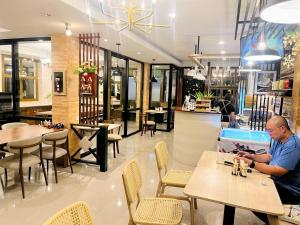 a man sitting at a table in a restaurant at Silpasala StayZ in Sathani Ban Hua Mak