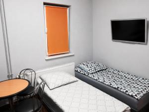 a small room with a bed and a table and a tv at Domek STABOL in Kołobrzeg