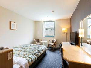 a hotel room with a bed and a desk and a television at Tsubamesanjo Washington Hotel in Sanjo