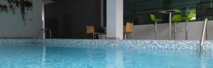 a large blue swimming pool in a room with chairs at Résidences Aya in Abidjan