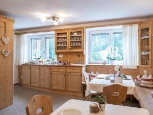a kitchen with wooden cabinets and tables and windows at Lettnerhof Bnb Family Suite 4 in Monguelfo