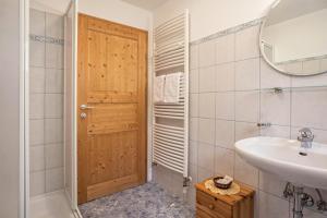 a bathroom with a sink and a wooden door at Bnb Lettnerhof Balcony Family Suite in Monguelfo +15 photos