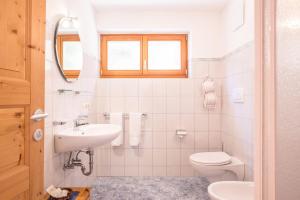 a white bathroom with a sink and a toilet at Lettnerhof bnb Family Suite 3 in Monguelfo +16 photos