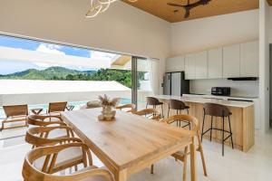 a kitchen and dining room with a wooden table and chairs at Modern Jungle Pool Villa in Mae Nam