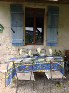 a blue table with four chairs and a window at Maison Les Fleuries in Saint-Quentin-de-Chalais