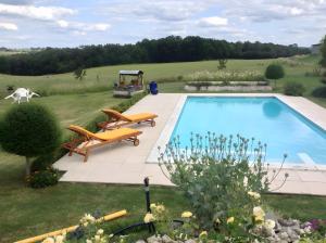 a swimming pool in the middle of a yard with two benches at Maison Les Fleuries in Saint-Quentin-de-Chalais