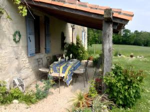 a table and chairs sitting under a porch at Maison Les Fleuries in Saint-Quentin-de-Chalais