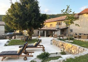a patio with two lounge chairs and a building at Villa Olmeto in Lupoglav