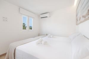 a white bedroom with a white bed and a window at Apartamento las palmeras 2 Planta 3 in Cala Millor +17 photos