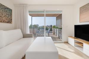 a living room with a white couch and a television at Apartamento las palmeras 2 Planta 3 in Cala Millor