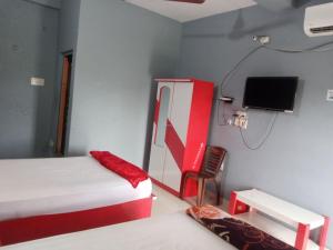 a bedroom with a red and white bed and a tv at Subhalaxmi Hotel and Lodge in Bahāsi