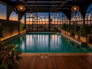 a swimming pool in a building with a sunset in the background at The Belmonte House by Noventa - Rooftop Pool Hotel in Udaipur in Udaipur