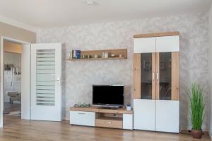 a living room with a tv and a desk with a television at Ferienwohnung Dorfliebe in Gerolfingen