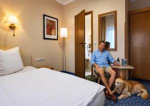 a man sitting in a hotel room with a dog at Garden Depandance Am Bach in Kurort Altenberg +44 photos