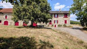an old stone building with red doors and a tree at Villetelle in Cheissoux