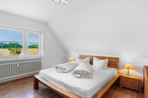 a white bedroom with a bed and a window at Fewo Tief Blick in Dornum