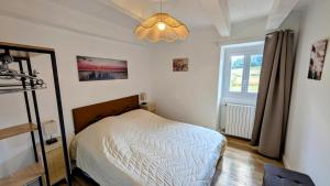 a bedroom with a bed and a window and a chandelier at Petit villetelle in Cheissoux
