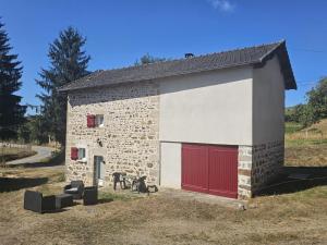 a stone building with red doors and a horse outside at Petit villetelle in Cheissoux