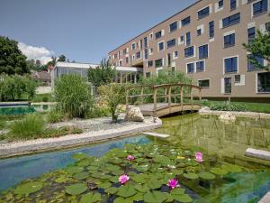 a pond with a bridge and flowers and a building at Hotel Die Zeit in Sankt Veit an der Glan