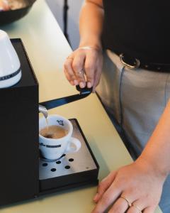 a person is making a cup of coffee at One Suite Hotel - Zollhaus in Bern