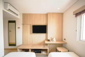 a room with two beds and a tv on a wall at Kotta Kyu Hotel Semarang in Semarang
