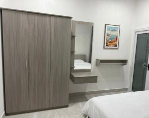 a bedroom with a bed and a wardrobe and a mirror at Daisy Stay Dhaandhoo in Nilandhoo