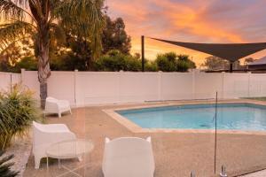 a swimming pool with white chairs and a table at Yarra Palms in Yarrawonga +17 photos