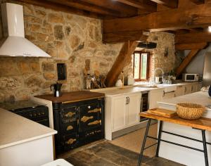 a kitchen with white cabinets and a stone wall at Laguna de Valfría in Fresneda