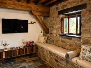 a living room with a stone wall with a couch and a tv at Laguna de Valfría in Fresneda