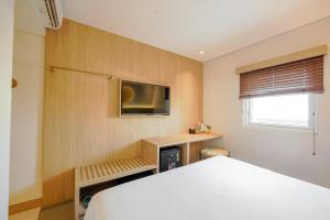 a bedroom with a bed and a tv on the wall at Kotta Kyu Hotel Semarang in Semarang