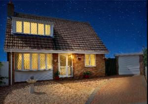 a brick house at night with the lights on at Stunning Holiday Cottage nr Skegness in Sunny Chapel St Leonards Just mins from the Beach & Attractions - Perfect for Couples & Family's who love to Relax but want Exciting Adventures nearby! Large Pet Friendly garden! in Chapel Saint Leonards