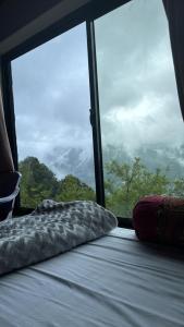 a bed in a room with a large window at Galiyat Peak in Abbottabad +1 photo