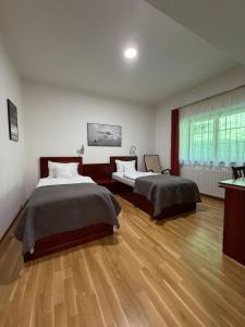 two beds in a room with wooden floors at Hotel a Restaurant Výpřež in Děčín