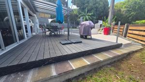 a wooden porch with an umbrella and a table and chairs at Entre Mer et Volcan ,piscine chauffée au tampon in Bel Air +1 photo