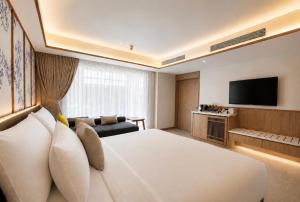 a hotel room with a large bed and a television at Myneris Hotel, Phuket Karon Beach in Karon Beach