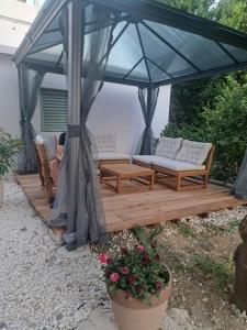 a gazebo with two couches on a wooden deck at Luni Studio Apartment with garden in Kaštela
